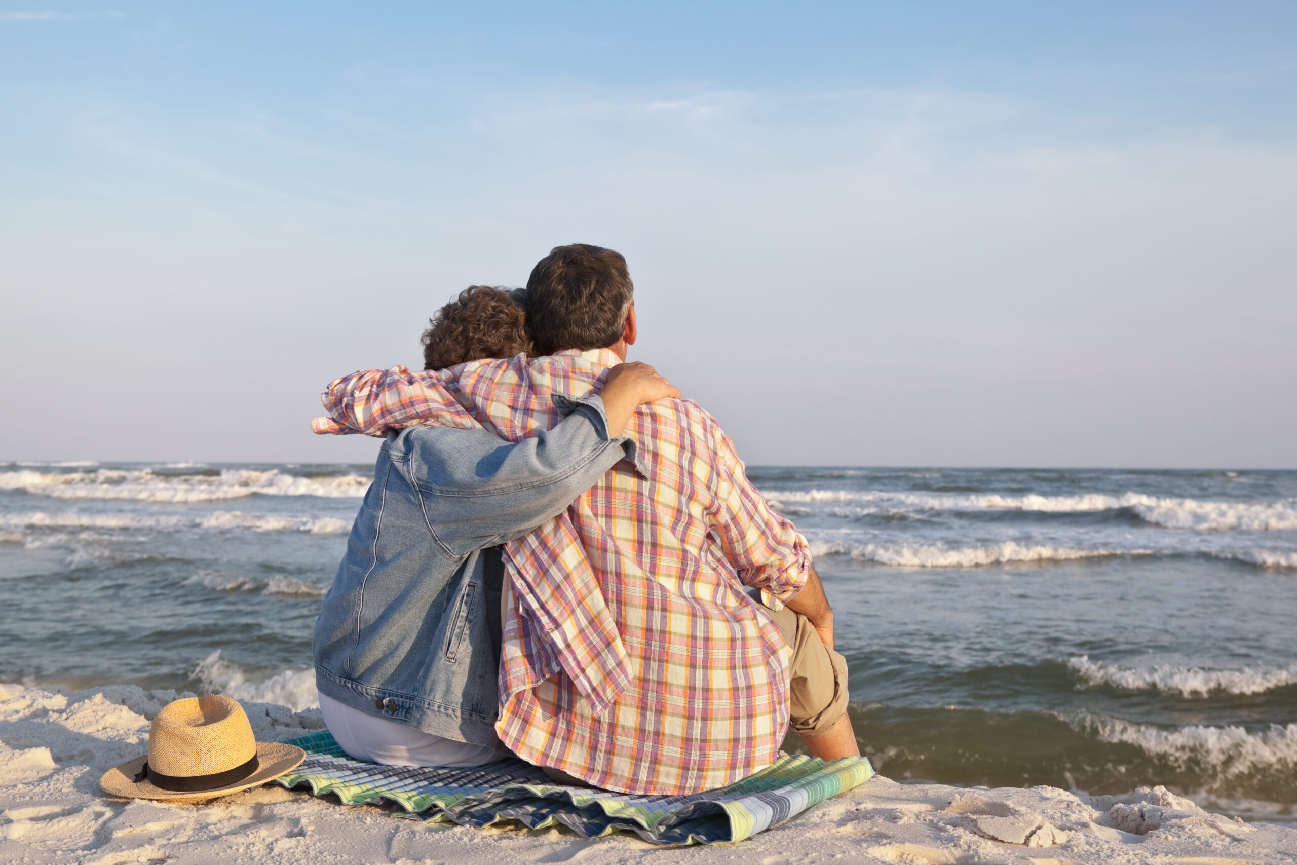 couple sitting and embrassing while watching ocean