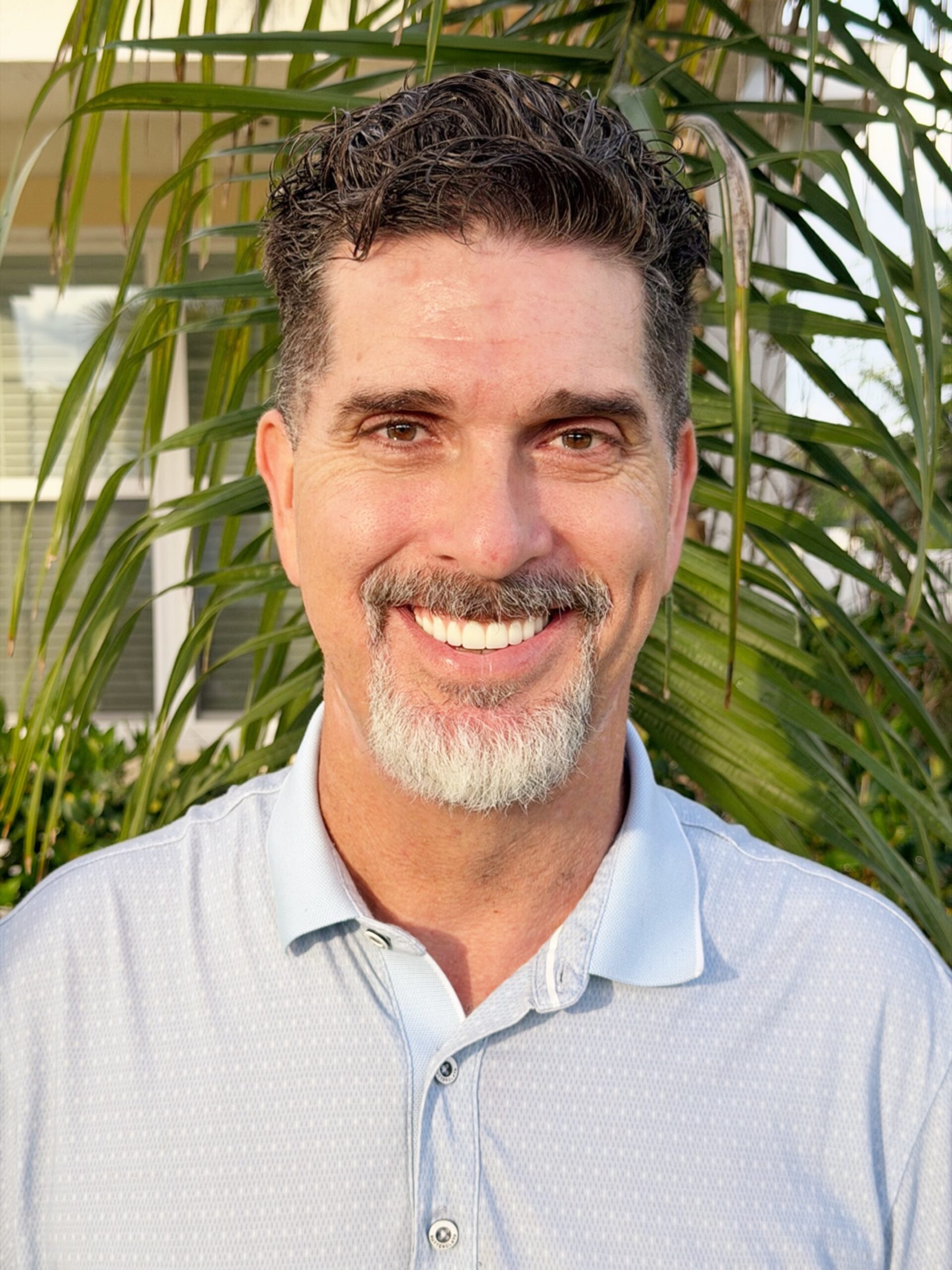 Close up of man standing in front of palm smiling