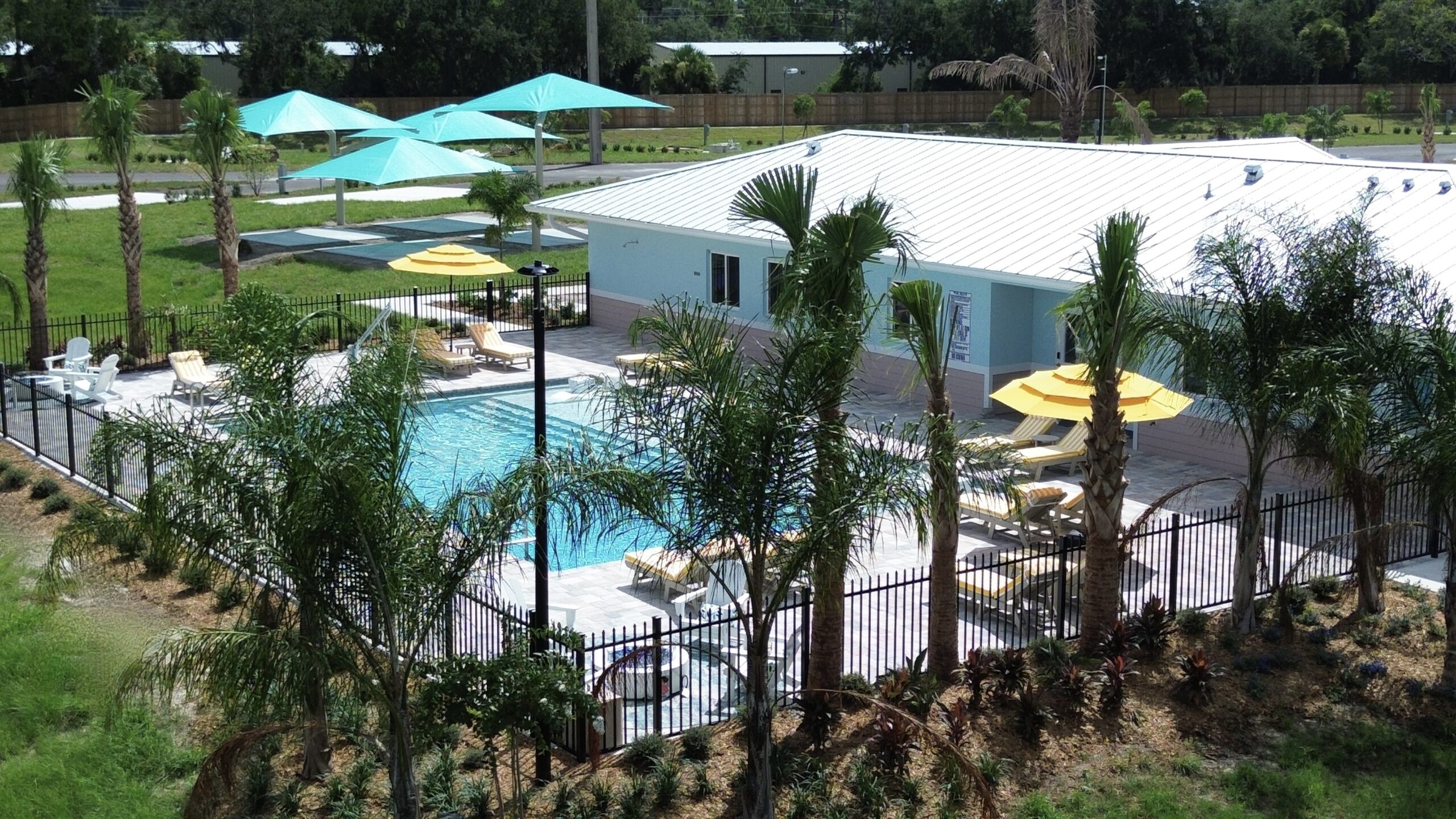 Resort pool with chairs, umbrellas and fire pits. all on lake side with palm trees.